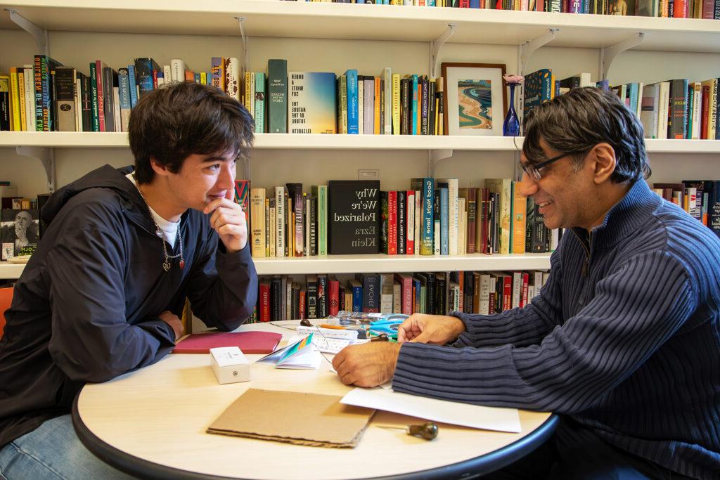 Professor and a student working on a project at a table.